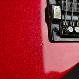Close-up of a red glitter-finish guitar body with part of the black bridge and hardware visible.