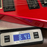 A red electric guitar body resting on a digital scale displaying 8.41 oz, with the scale brand Wetzell Max visible.