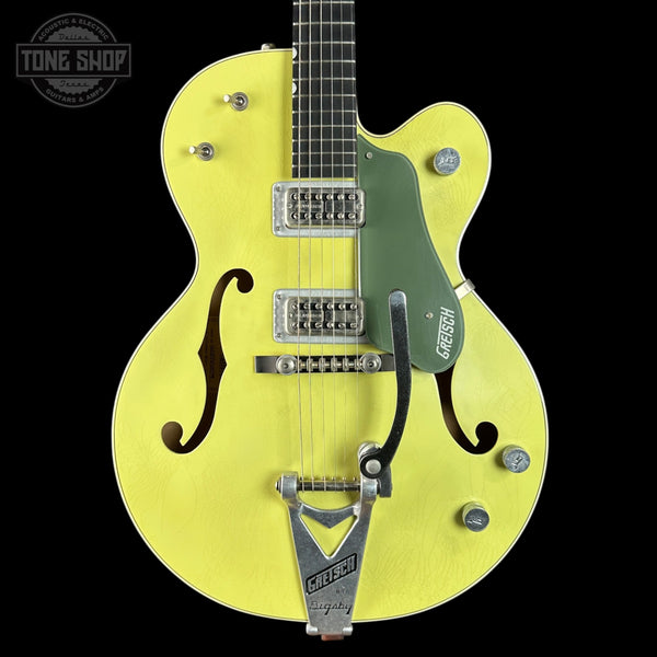 Yellow electric guitar with green pickguard on a black background, featuring Gretsch branding.