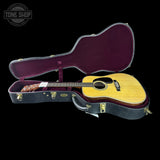 Acoustic guitar in a hard-shell case with 'Tone Shop' logo.