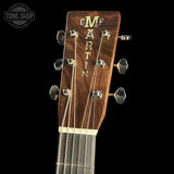 Close-up of a Martin guitar headstock with brand name on a black background