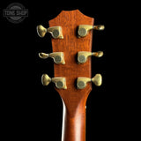 Close-up of the headstock of a guitar, showing six gold-toned tuning pegs on a rich reddish-brown wood finish, set against a solid black background.