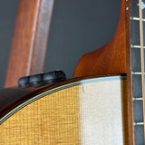 Close-up detail of an acoustic guitar body showing the sound hole, black tuners, maple wood top, and part of the dark fretboard.