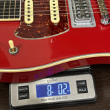 Red electric guitar on a digital scale displaying weight