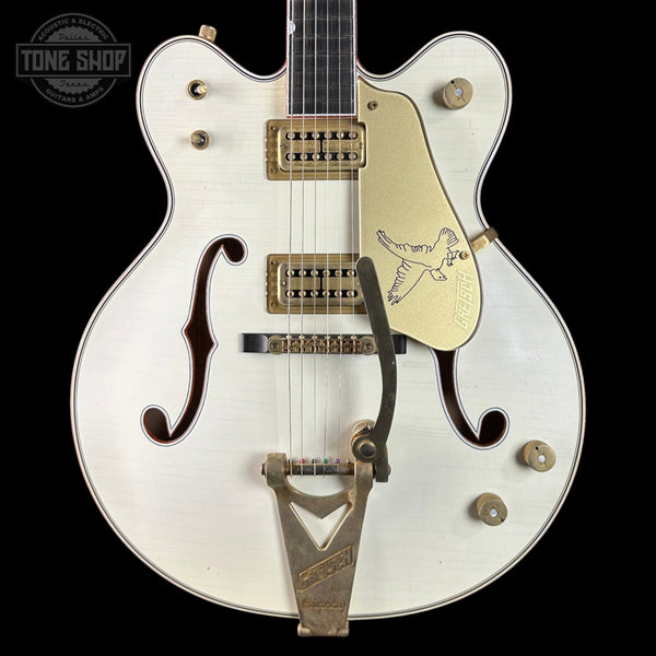 White electric guitar with gold hardware on a black background, featuring the Tone Shop logo.