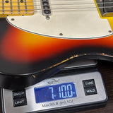 Close-up of a sunburst electric guitar resting on a digital scale showing a weight of 7.07 lbs.