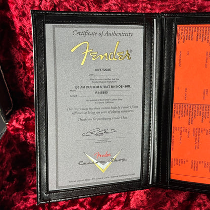 Fender certificate of authenticity in a black leather case on a red textured surface