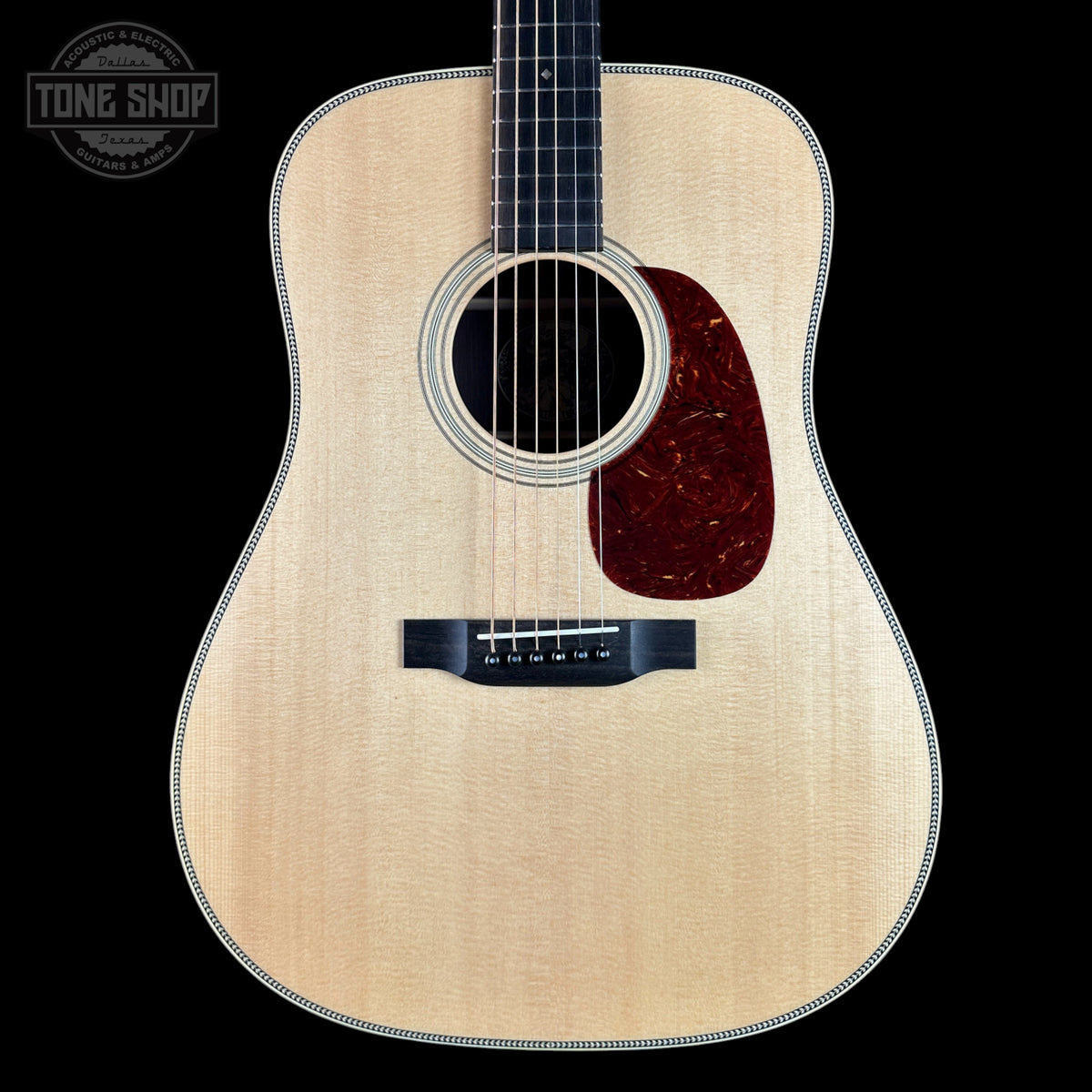 Acoustic guitar with a visible brand logo on a black background