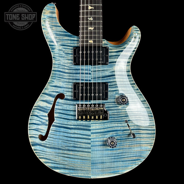 Blue electric guitar with a black pickguard on a black background, featuring the Tone Shop logo.