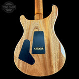 Back view of a wooden electric guitar with a visible brand logo in the corner.