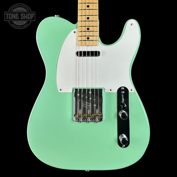 Green electric guitar with a white pickguard on a black background, featuring the Tone Shop logo.
