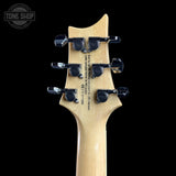 Close-up rear view of an electric guitar headstock in a natural maple finish with black tuning pegs, shown against a solid black background. A Tone Shop watermark is visible in the top-left corner.