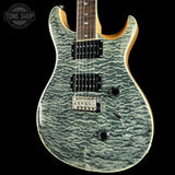 A close-up of an electric guitar body featuring a distinctive wavy, marbled greenish-gray flamed maple finish, with a black pickguard, dual humbucker pickups, and a light natural wood neck visible at the top, set against a solid black background.