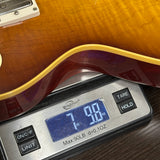 Guitar being weighed on a digital scale with a wooden finish.