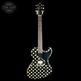 A black electric guitar with a white polka-dot pattern on the body, shown against a solid black background. The brand name 'Gibson' is visible on the headstock, and a 'Tone Shop' watermark is in the top-left corner.