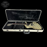 An electric guitar with a cream body covered in black polka dots, resting inside an open white hard case with black velvet lining on a black background. A Tone Shop logo is visible in the top-left corner.