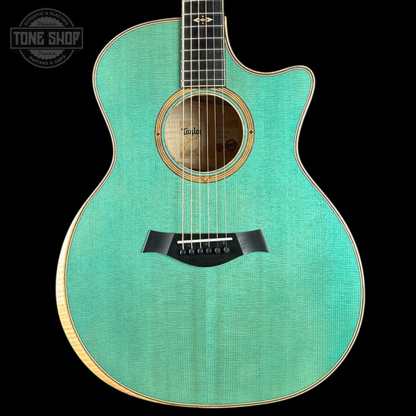 Turquoise acoustic guitar with a visible brand logo on a black background
