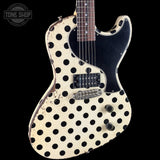 A classic electric guitar with a cream-colored body covered in black polka dots, a black pickguard, and a dark brown neck, shown against a solid black background.