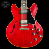 Red electric guitar with a black background, featuring the Tone Shop logo.