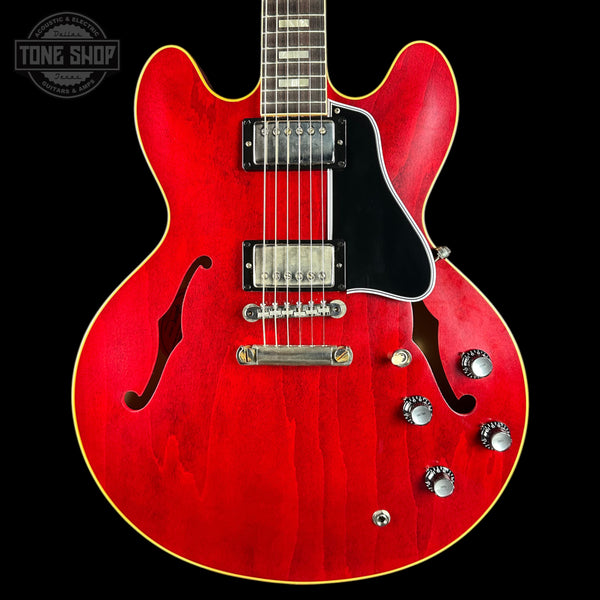Red electric guitar with a black background, featuring the Tone Shop logo.