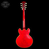 Red electric guitar with a 'Tone Shop' logo in the corner