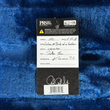 A product tag for a PRS Vintage Collection wool blanket, laid flat on a textured blue fleece surface. The tag details the product's stringing, model, serial number, and assembly by Final Checka.