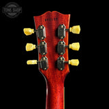 Close-up of a red guitar headstock with tuning pegs on a black background, featuring 'Tone Shop' branding.