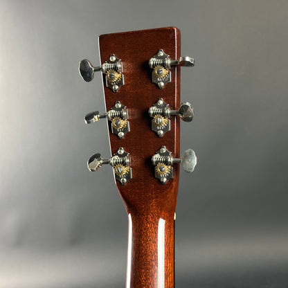 Close-up of a guitar headstock with tuning pegs on a gray background