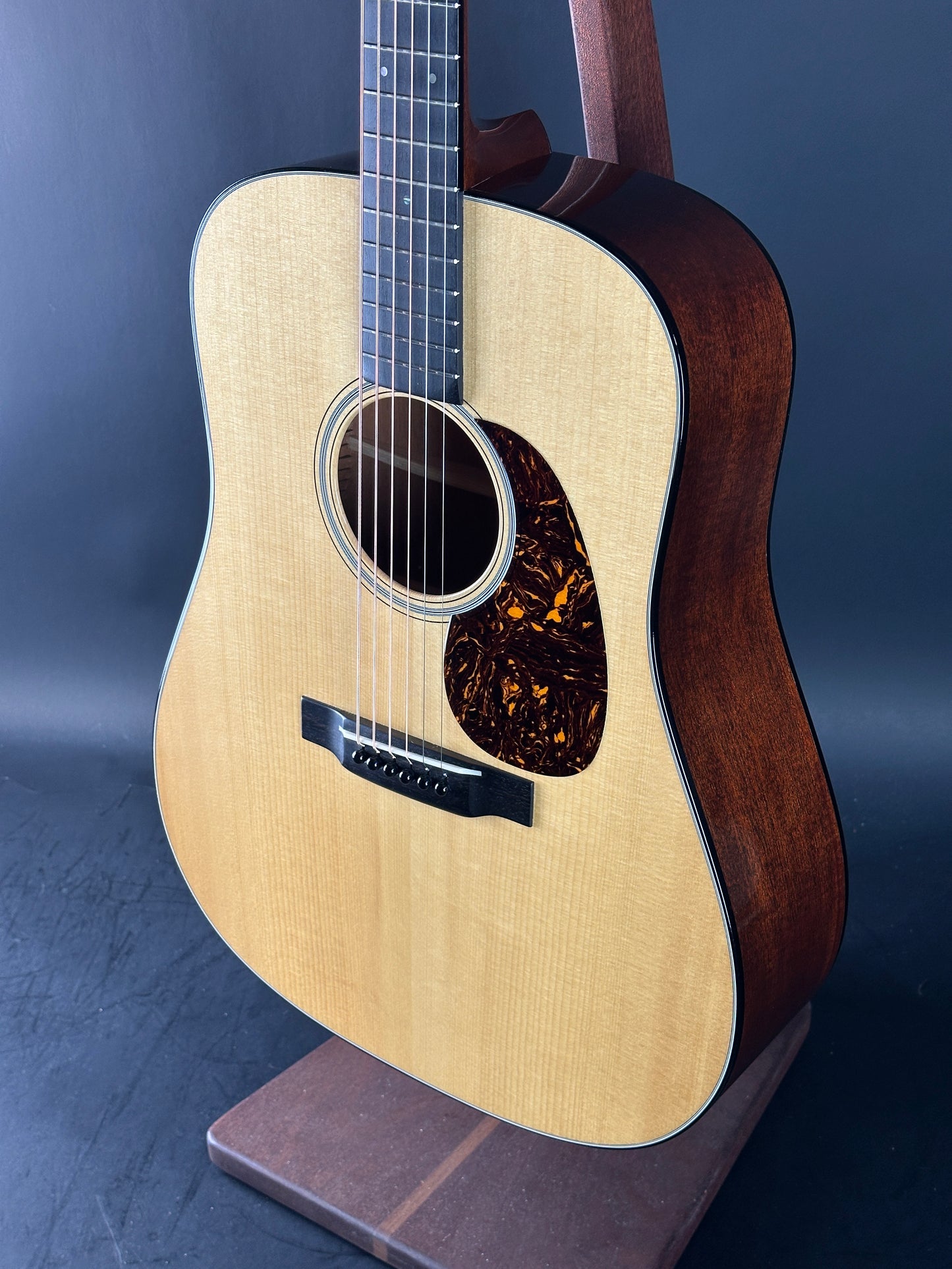 Acoustic guitar with a wooden body and dark brown neck on a blue background