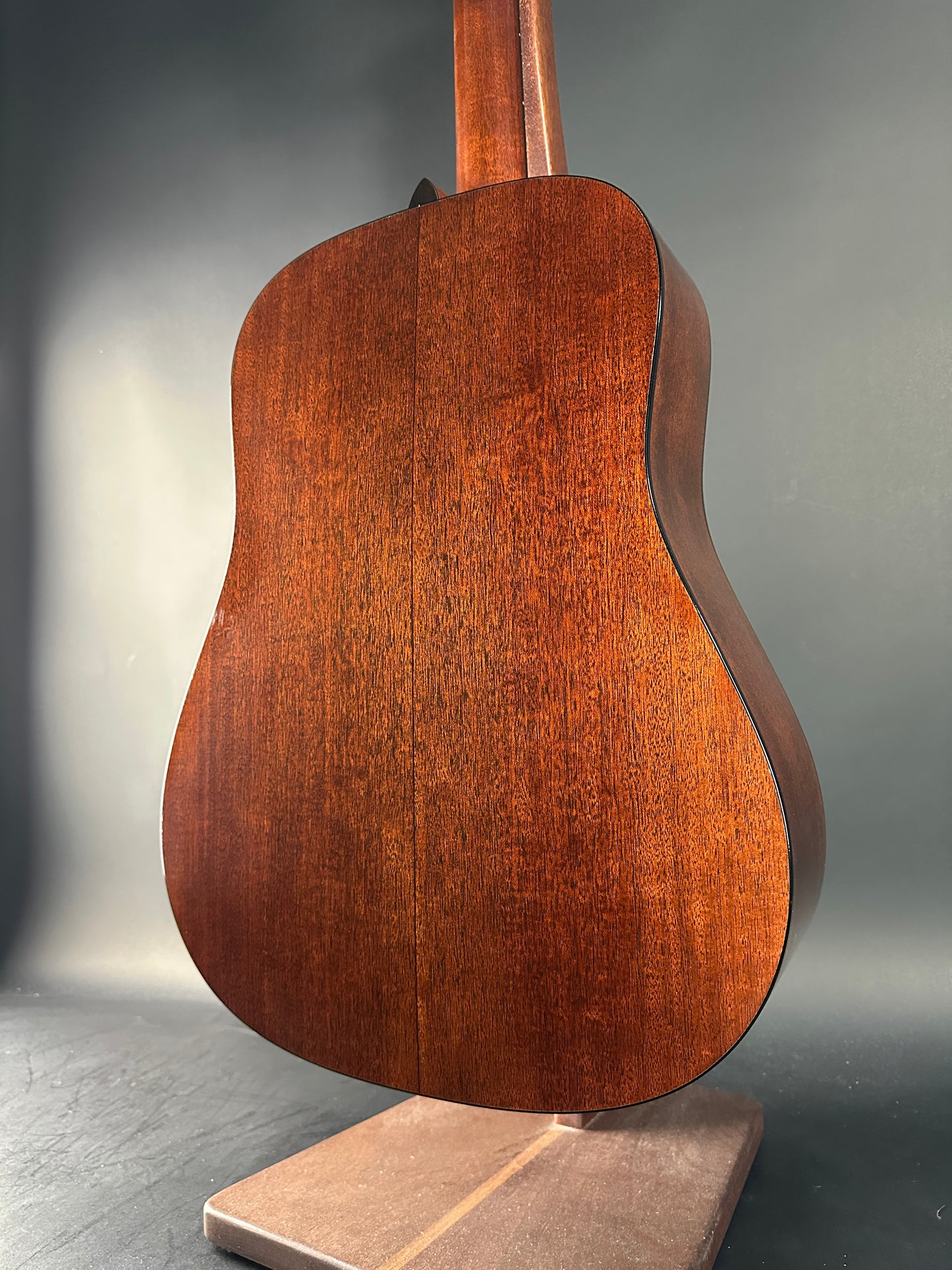 Close-up of a wooden acoustic guitar body on a gray background
