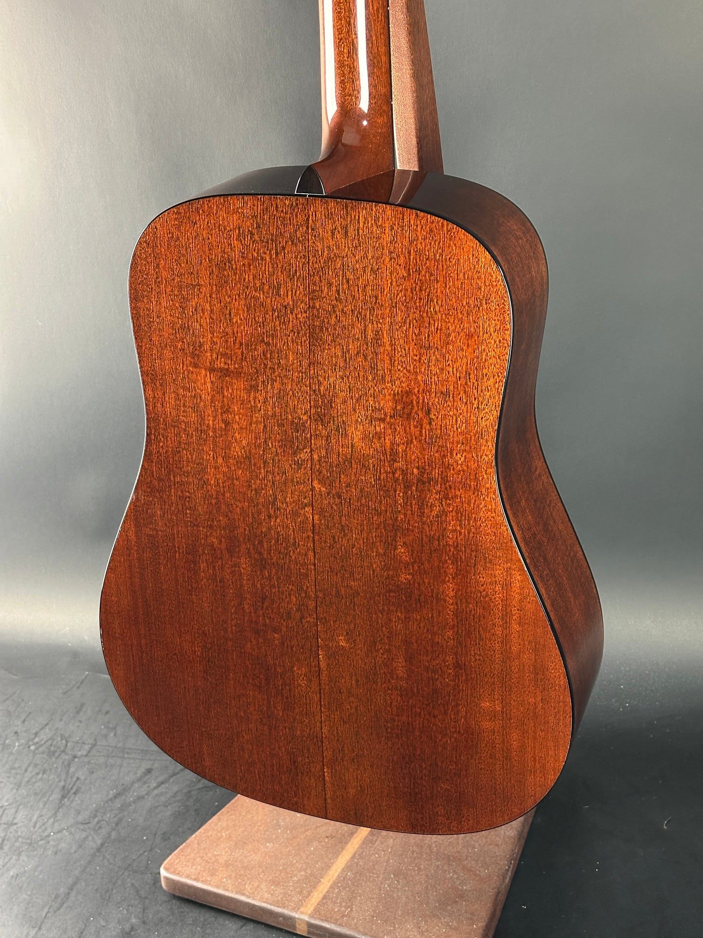 Close-up of a wooden acoustic guitar body on a gray background