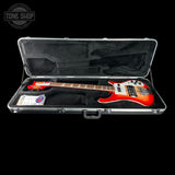 Red electric bass guitar in a black case with 'Tone Shop' logo.