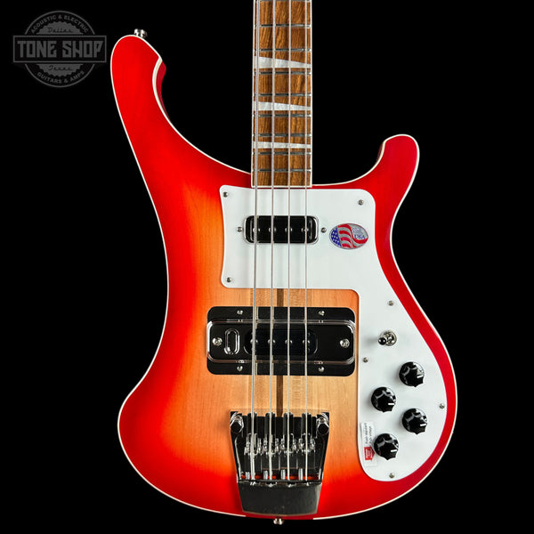Electric bass guitar with a red and white finish on a black background, featuring the Tone Shop logo.