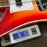 Electric guitar being weighed on a digital scale with a red and white finish.