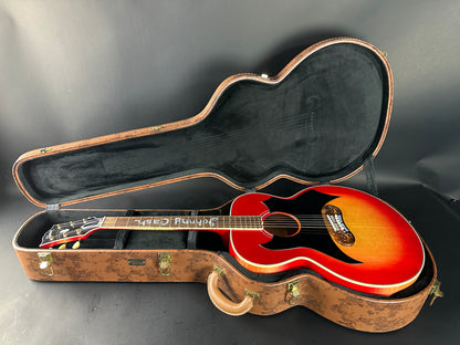 Red acoustic guitar in a case on a gray background