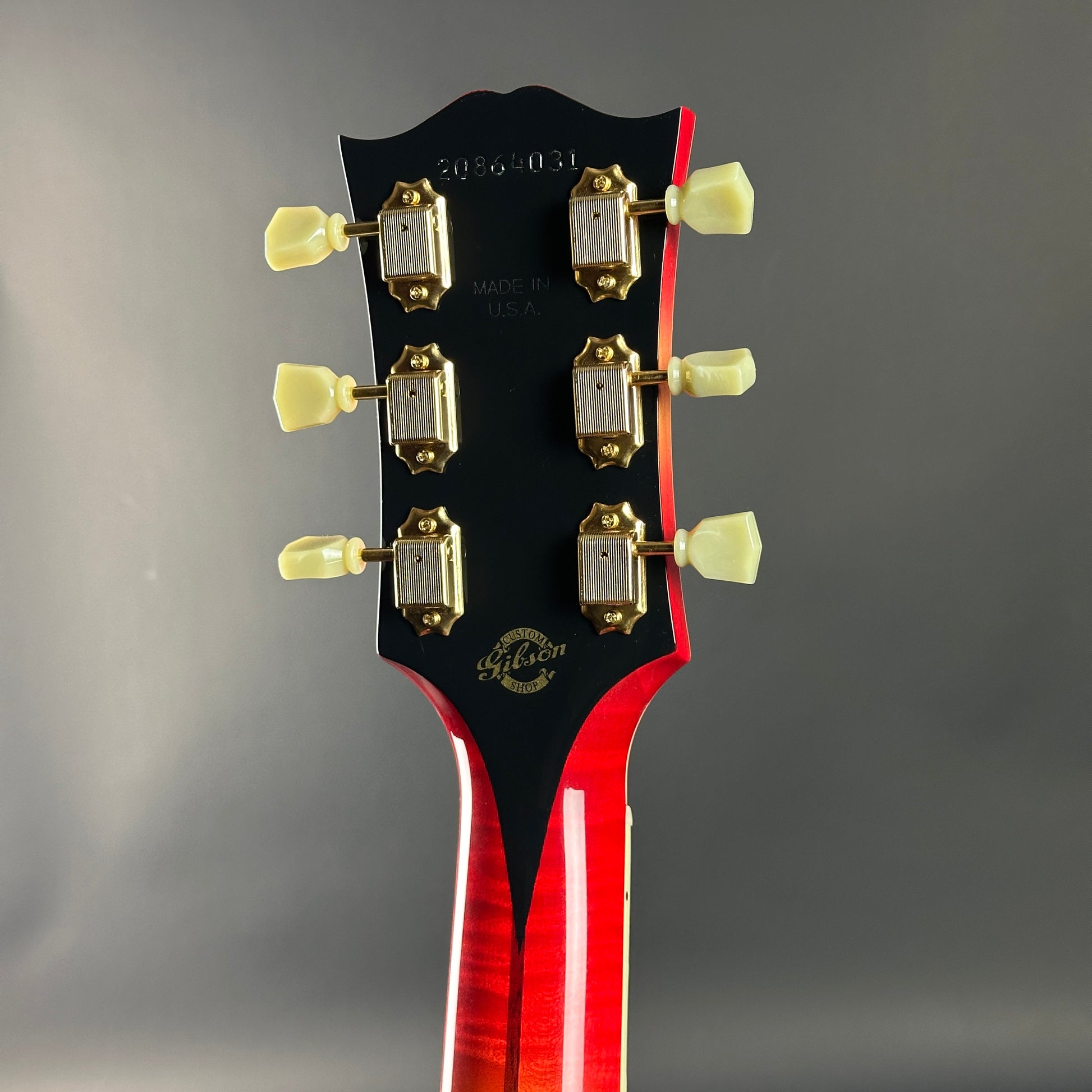 Guitar headstock with tuning pegs on a gray background
