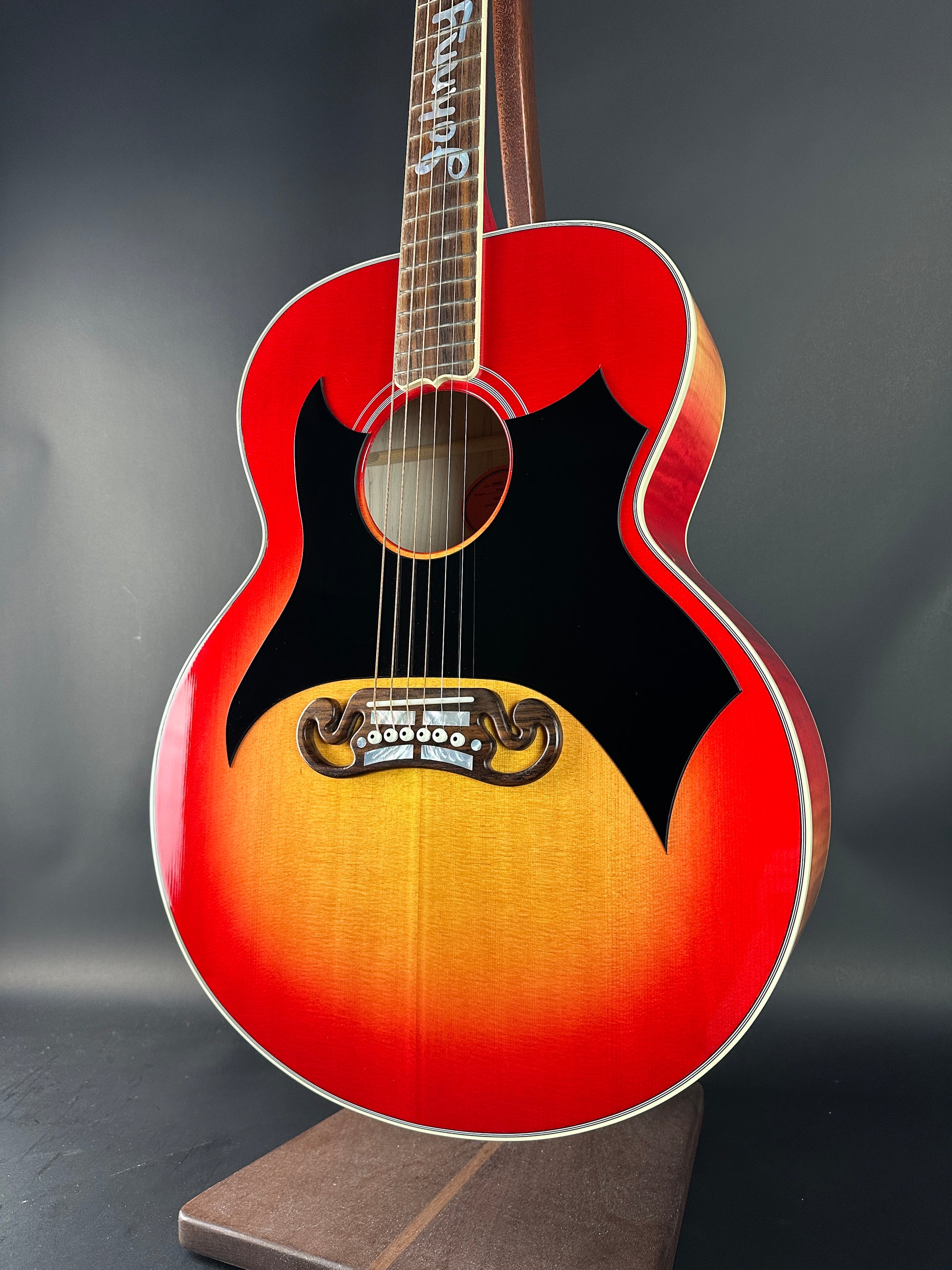 Red acoustic guitar with a sunburst finish on a dark background