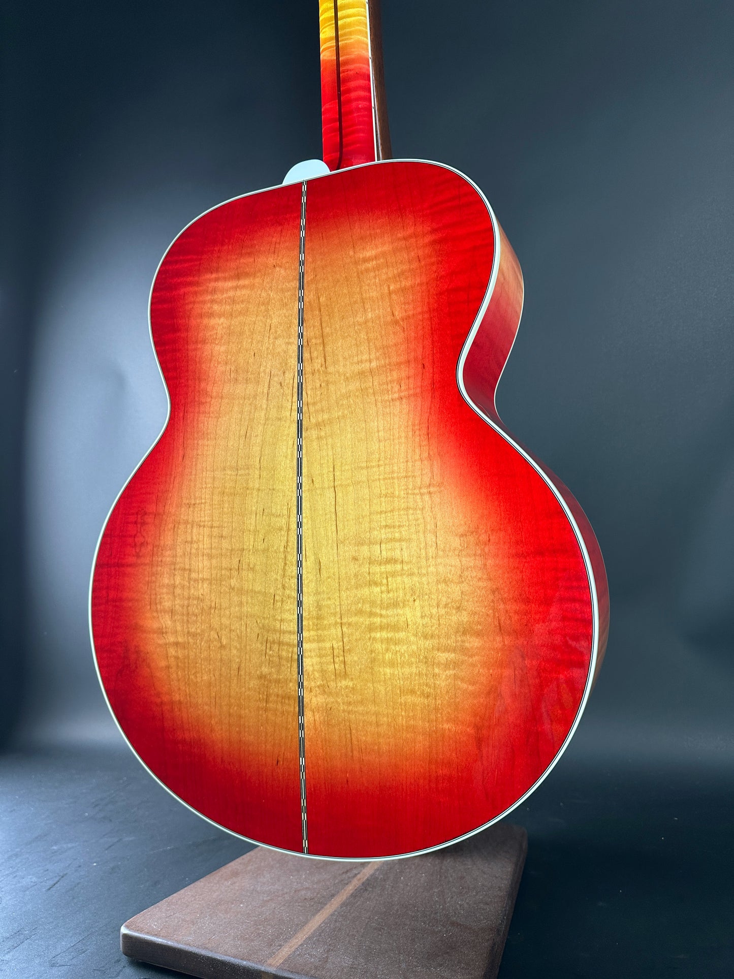 Acoustic guitar with a sunburst finish on a stand against a dark background