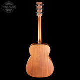 The back view of a wooden acoustic guitar against a solid black background, featuring a warm brown wood finish and a Tone Shop watermark in the top left corner.