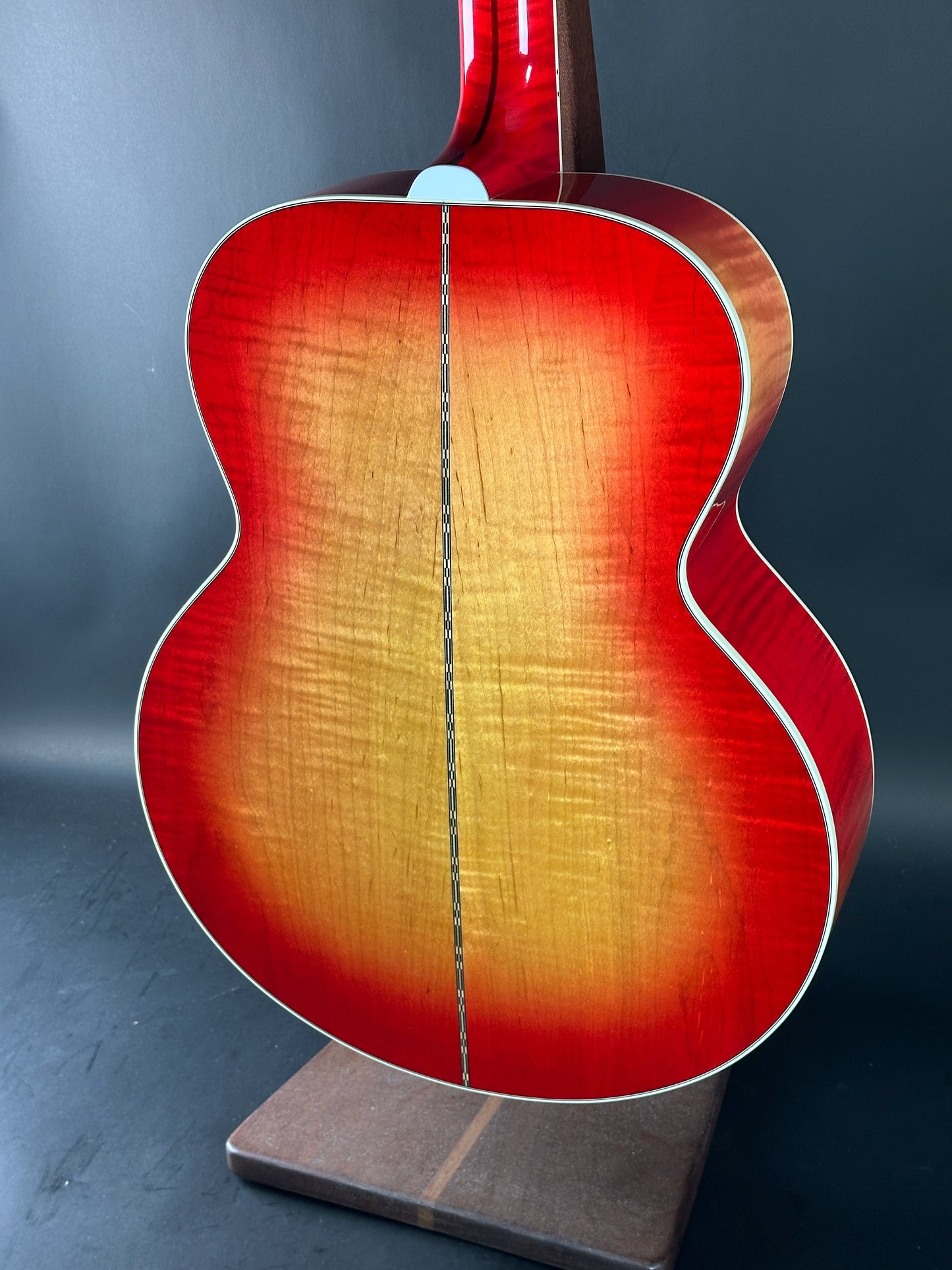Red acoustic guitar on a stand against a dark background