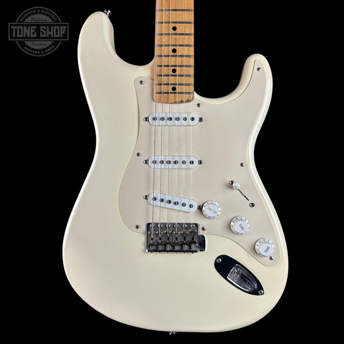 Cream-colored electric guitar with a maple neck, featuring three single-coil pickups, a black bridge, and white control knobs, shown against a black background with a Tone Shop watermark.