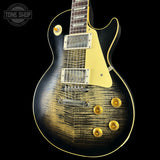Electric guitar with a black and gold finish on a black background, featuring the Tone Shop logo.