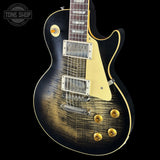 Electric guitar with a black and gold finish on a black background, featuring the Tone Shop logo.
