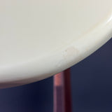 Close-up of a white curved surface, likely a chair or stool rim, showing scuffs and wear marks against a dark blue background.