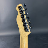 Close-up of a guitar headstock with tuning pegs on a dark gray background