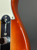 Close-up of a guitar's control knobs and body on a gray background