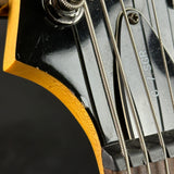 Close-up detail of an electric guitar headstock and neck, showing a glossy black finish, natural wood edge, metal tuning pegs, and strings with 'C-7 SGR' printed on the pickguard.