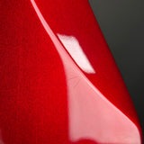 Close-up of a glossy red curved surface with a bright white reflection against a dark gray background.
