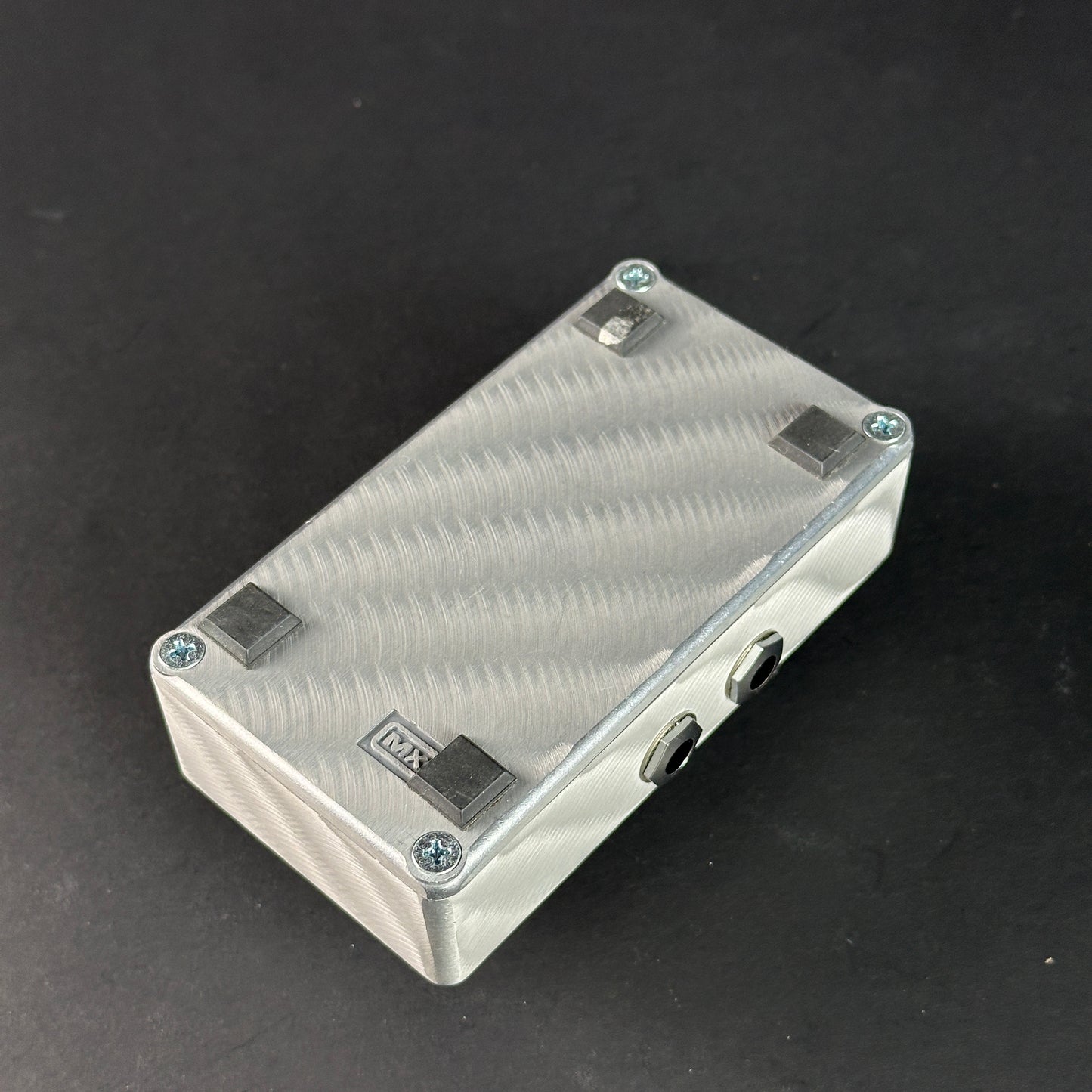 Metallic rectangular box with textured surface on a black background