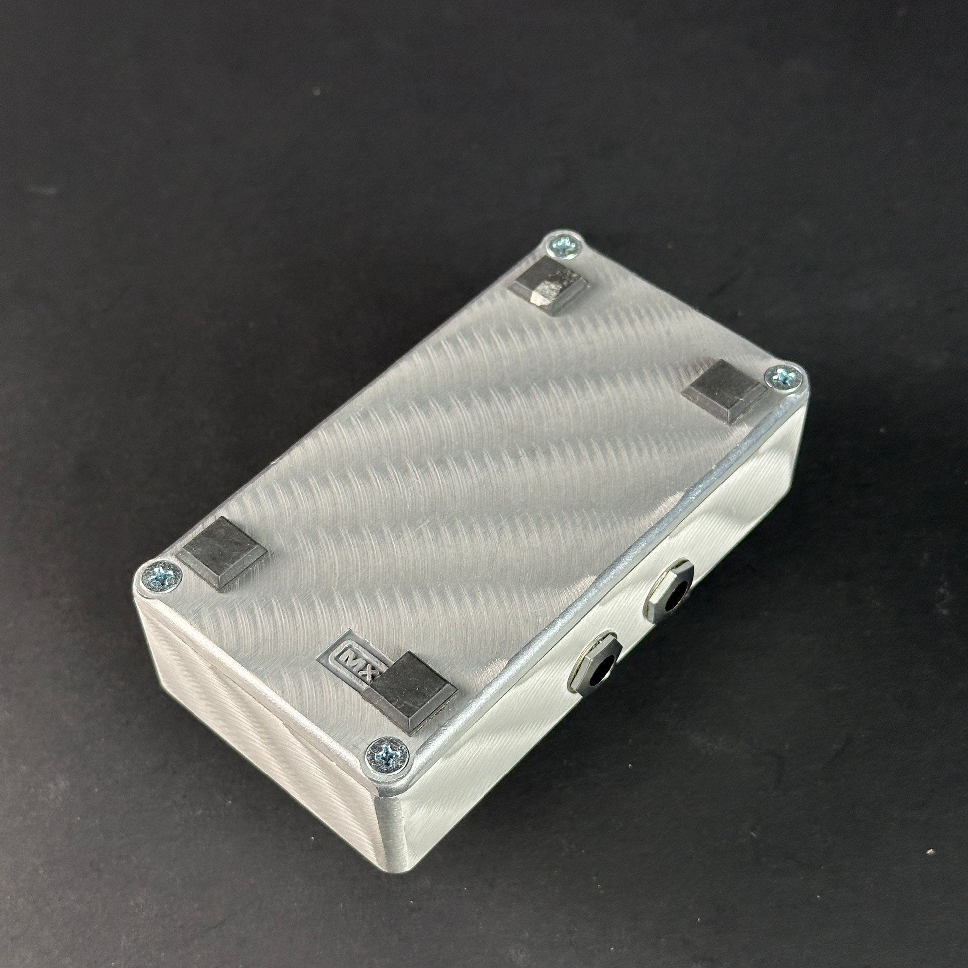 Metallic rectangular box with textured surface on a black background